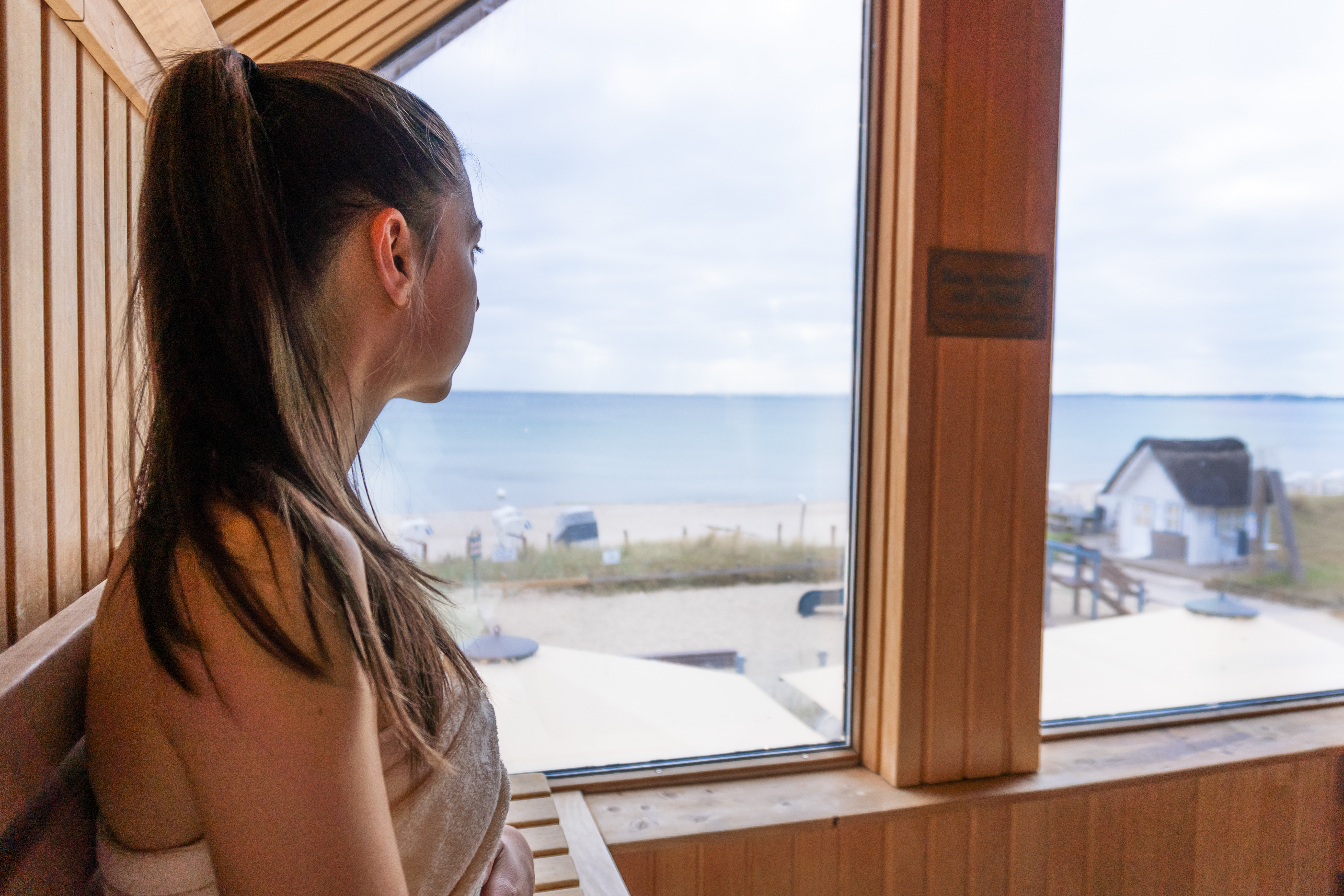 Cara sitzt in einer Sauna und schaut raus. 