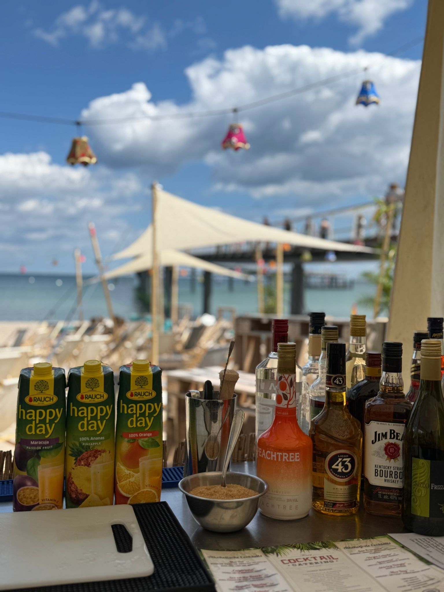 Getränke die auf einem Tisch stehen und im Hintergrund eine Lounge am Strand