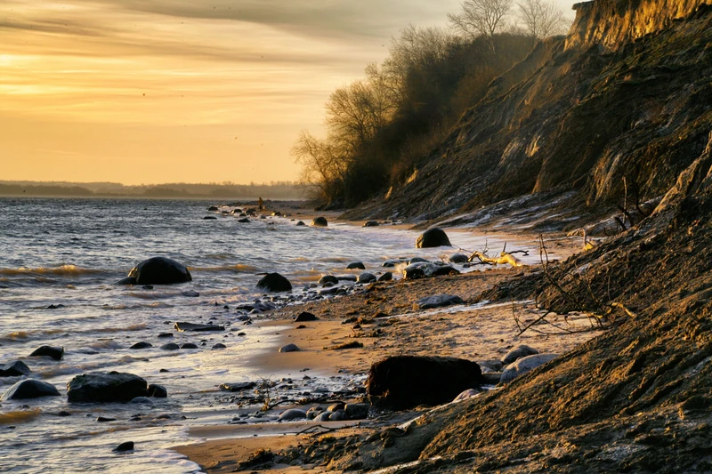 Steiniger Strandabschnitt mit kleiner Steilküste im Abendrot
