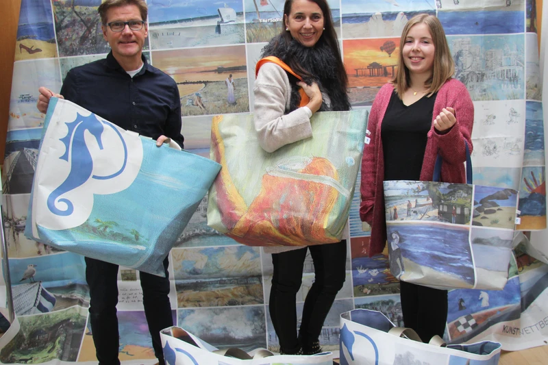 Drei Personen präsentieren große bunte Taschen mit Motiven