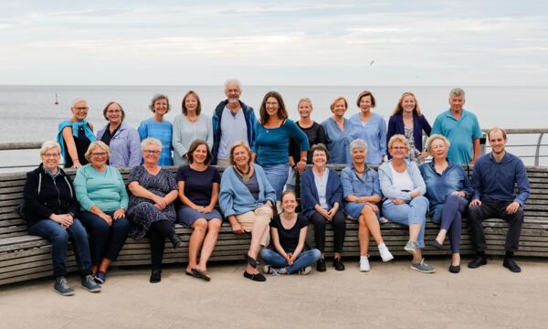 Ein Chor von mehreren Leuten, sitzen für ein Gruppenfoto zusammen.