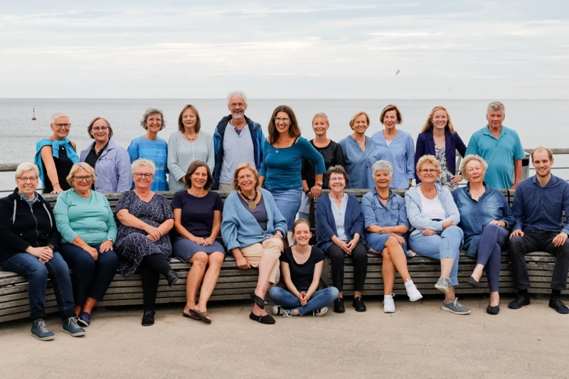 Ein Chor von mehreren Leuten, sitzen für ein Gruppenfoto zusammen.