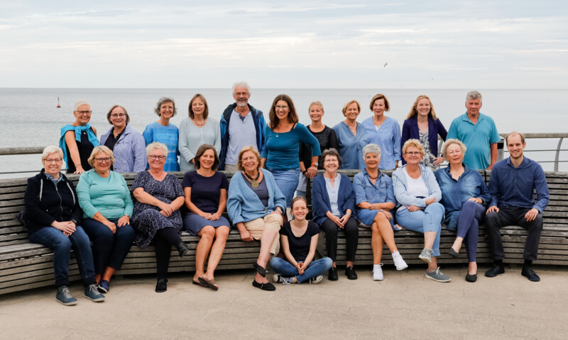 Ein Chor von mehreren Leuten, sitzen für ein Gruppenfoto zusammen.