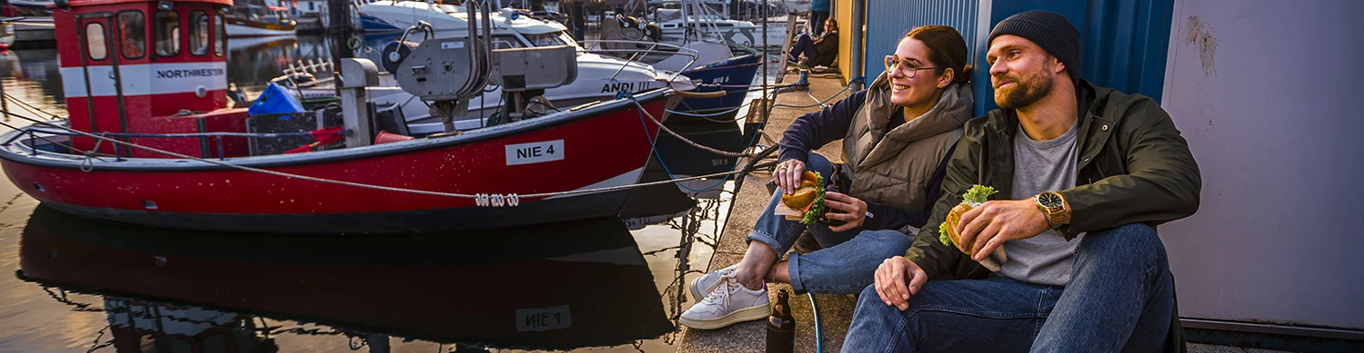 Pärchen sitzt mit Fischbrötchen am Niendorfer Hafen