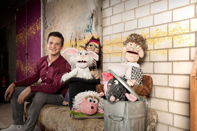 Bauchredner Tim Becker sitzt neben seinen Puppen