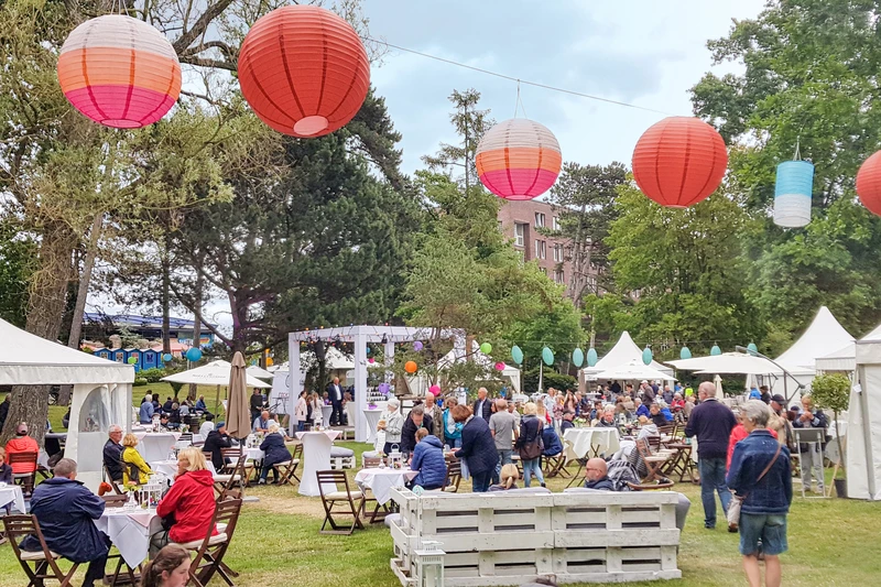 Festwiese mit vielen weißen Zelten und Tischen und Stühlen dazwischen.