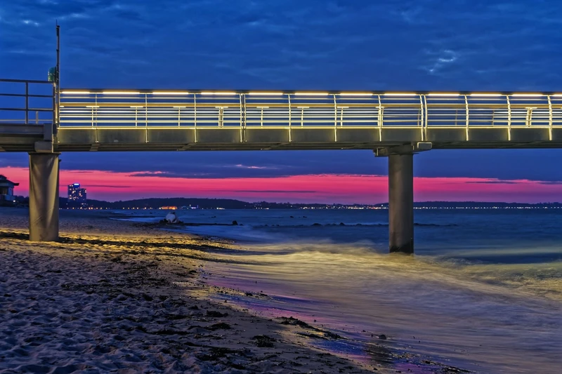 Teilausschnitt der Seebrücke in der Abenddämmerung mit pink erleuchtetem Himmel