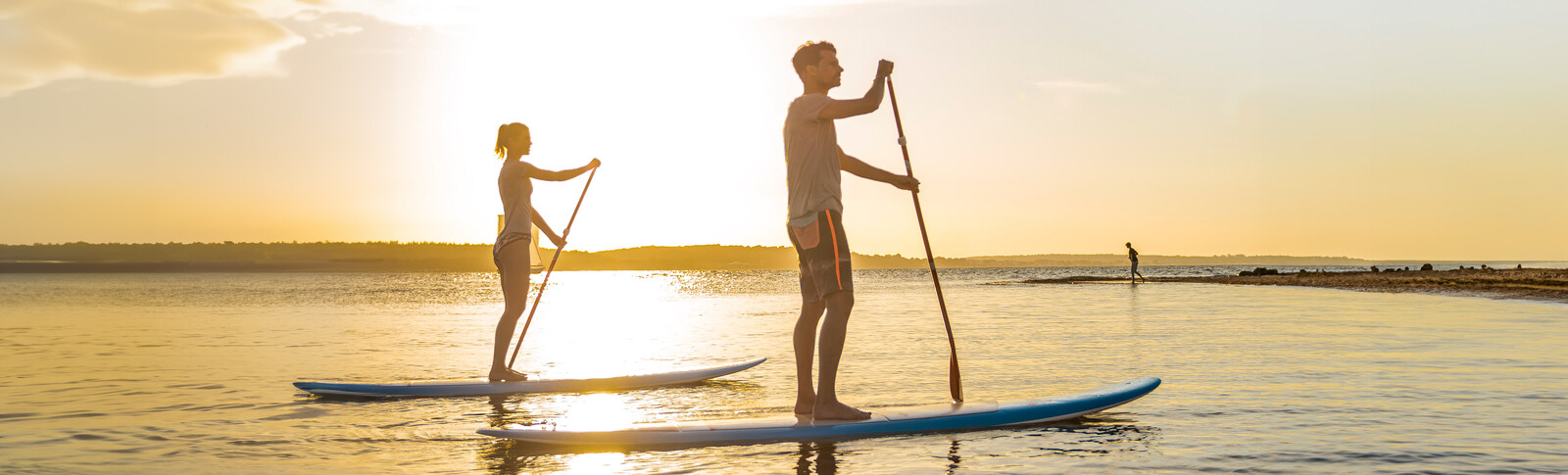 Pärchen auf SUPs im Sonnenuntergang