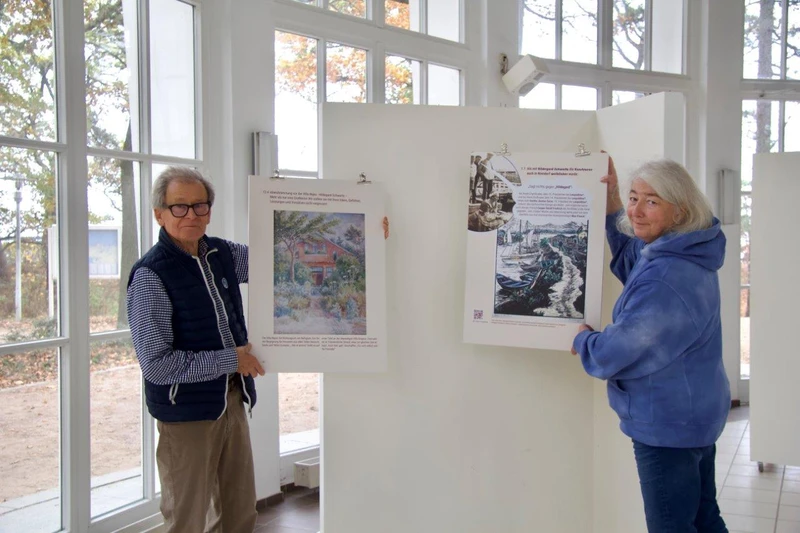 Ein Mann und eine Frau präsentieren zwei Kunstwerke in einem Ausstellungsraum