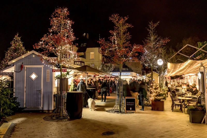 Beleuchtete Buden und Bäume auf dem Weihnachtsmarkt auf dem Timmendorfer Platz 