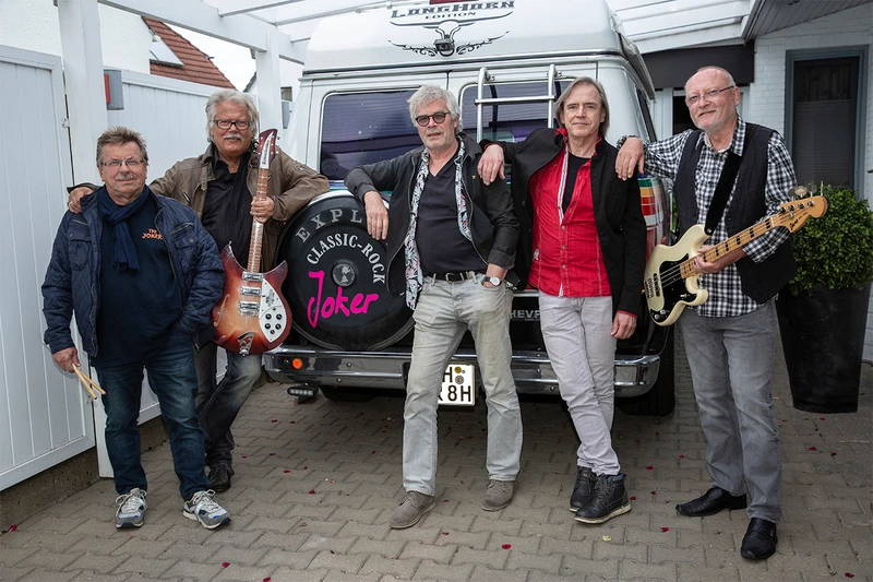 Bandfoto der Band The Joker neben ihrem Tourbus