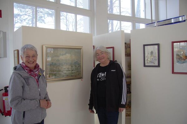 Zwei Frauen stehen vor mehreren Kunstwerken