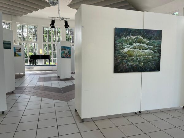 in einem hell beleuchteten Raum stehen Stellwände, auf denen man Kunstwerke sehen kann