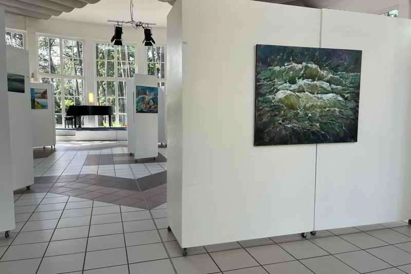 in einem hell beleuchteten Raum stehen Stellwände, auf denen man Kunstwerke sehen kann