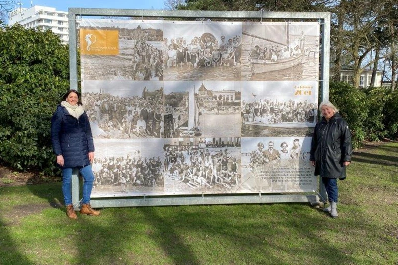 Silke Szymoniak und Stephanie Scheel vor einem Bild der "Goldenen Zwanziger" in einem Stahlrahmen