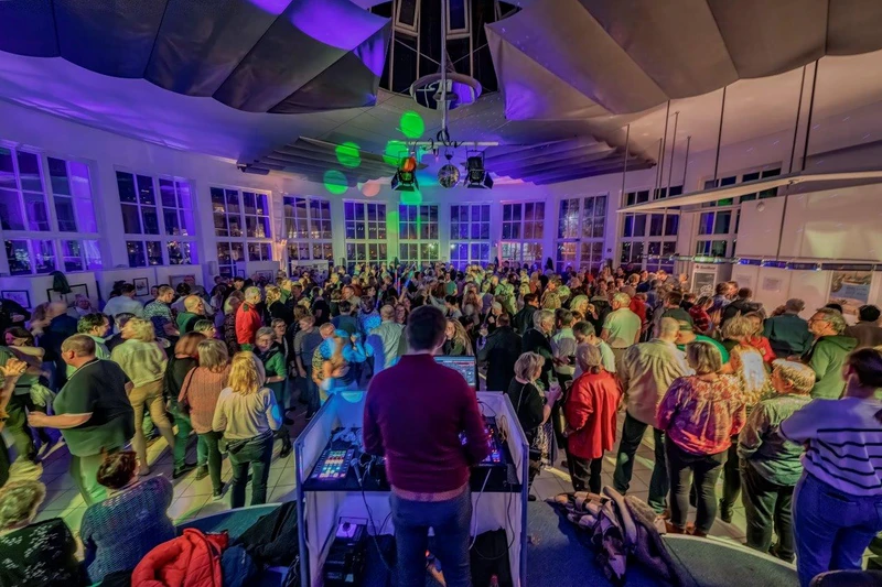 Viele tanzende Menschen in der Trinkkurhalle. Im Vordergrund des Fotos sieht man einen DJ mit dem Rücken zur Kamera.