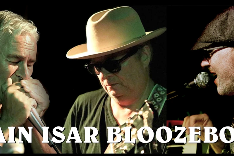Drei Männer in Nahaufnahme auf einer Bühne mit Mikrofonen und Gitarre. Sie tragen Sonnenbrillen und Hüte und darunter steht Main Isar Bloozeboyz