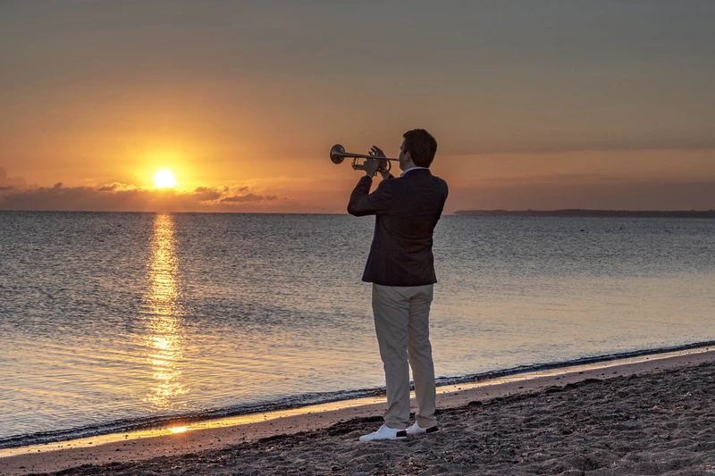 Martin Berner spielt Trompete beim Sonnenaufgang am Strand