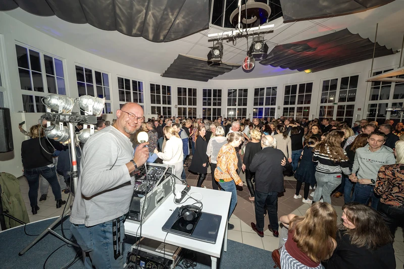 Im Hintergrund sieht man Leute tanzen, im Vordergrund sieht man den DJ.