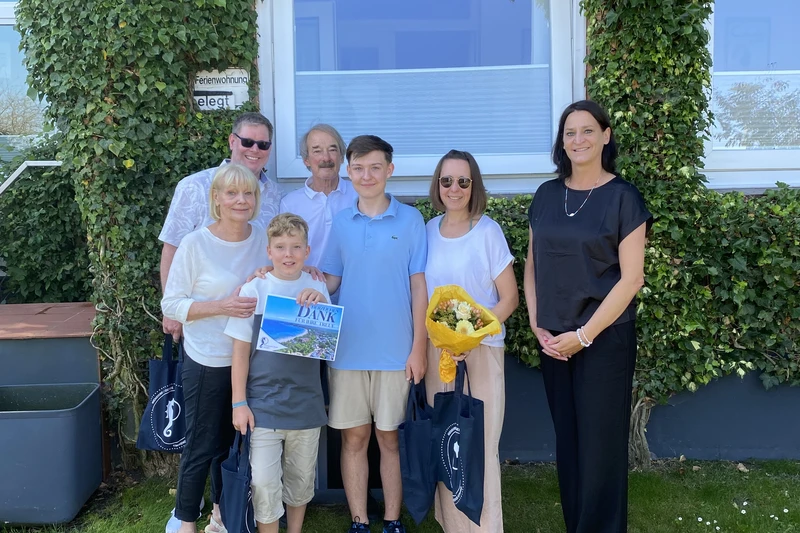 Foto einer Familie, die vor einer efeubewachsenen Wand steht
