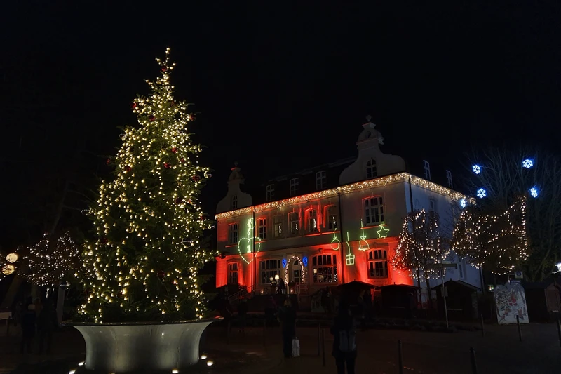 Weihnachtlich geschmücktes Gebäude mit geschmückter Tanne davor bei Nacht