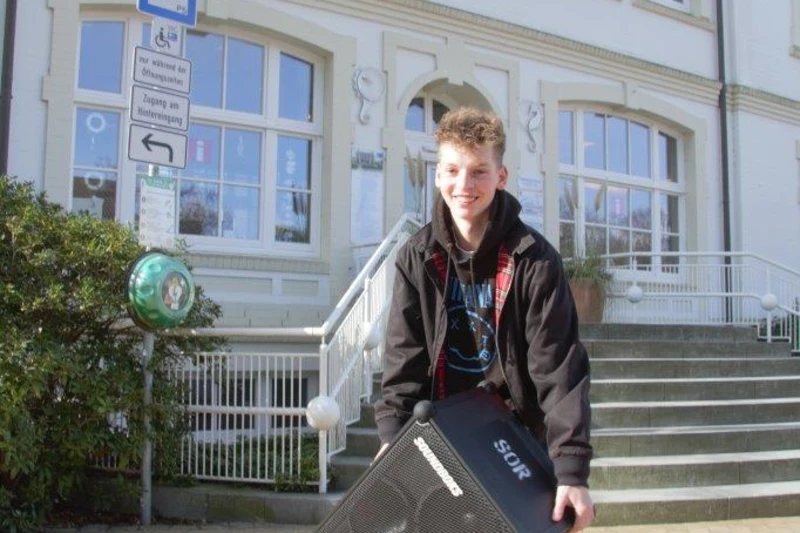 Jugendlicher steht mit einer Musikbox vor dem alten Rathaus in Timmendorfer Strand