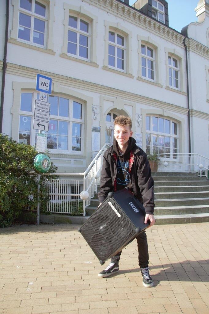 Jugendlicher steht mit einer Musikbox vor dem alten Rathaus in Timmendorfer Strand