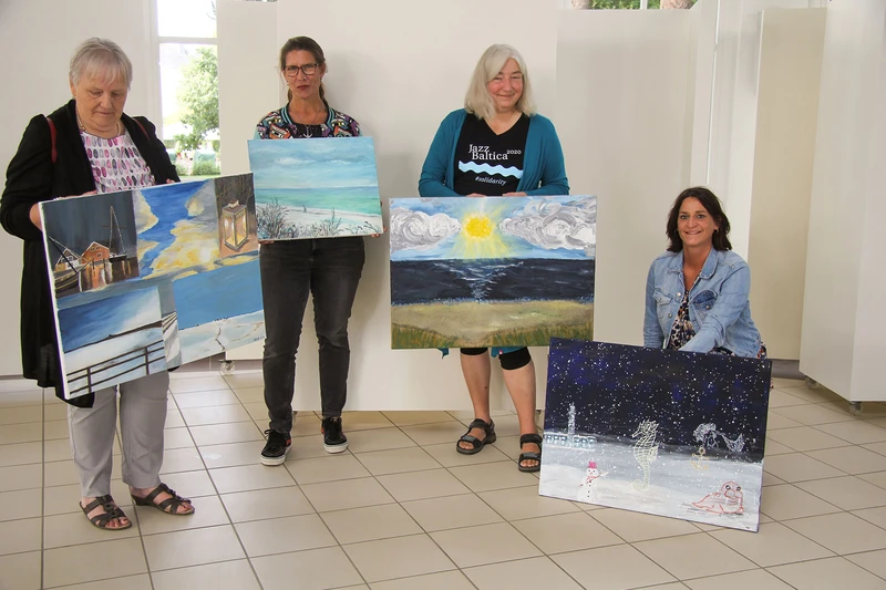 Vier Frauen präsentieren großformatige Kunstwerke