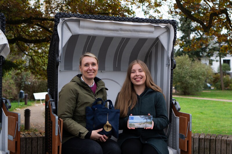 Zwei Mitarbeiterinnen aus dem Service der TSNT GmbH freuen sich im Strandkorb über die Wärmemomente
