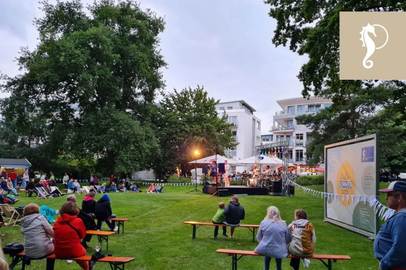 Konzert im Strandpark mit einer kleinen Bühne in der Mitte des Parks und Sitzgelegenheiten drum herum