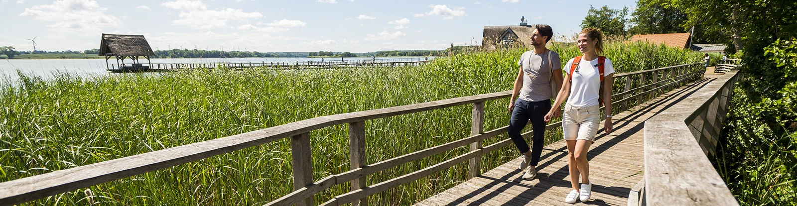 Mann und Frau wandern über Holzsteg im Sommer