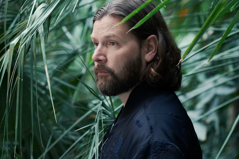 Foto von Rea Garvey zwischen großen grünen Pflanzen.