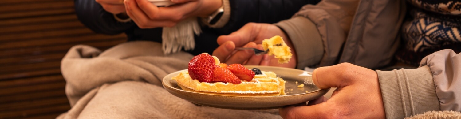 Mit Wolldecke eingemummelt gemütlich Waffeln essen