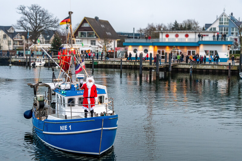 Der Weihnachtsmann kommt auf dem Fischerboot in den Niendorfer Hafen, um Süßigkeiten an die Kinder zu verteilen