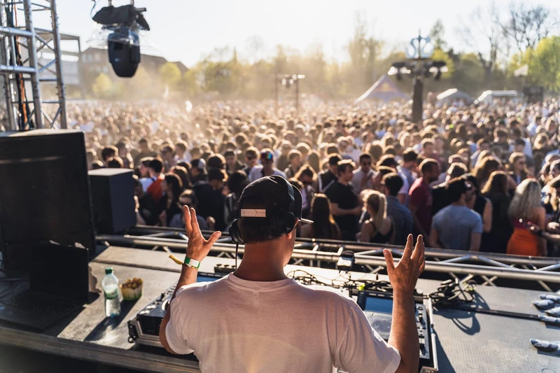 Foto einer Menschenmenge, die vor einem DJ tanzt