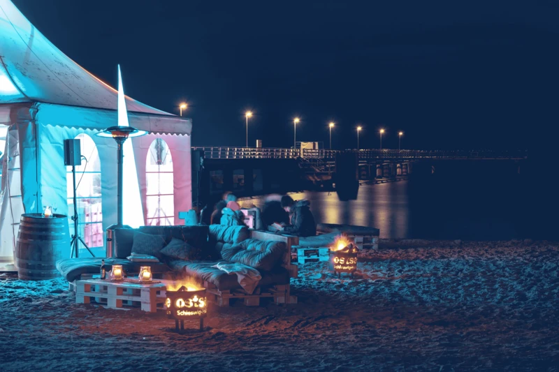 Festzelt und Sitzbänke am Strand bei Nacht