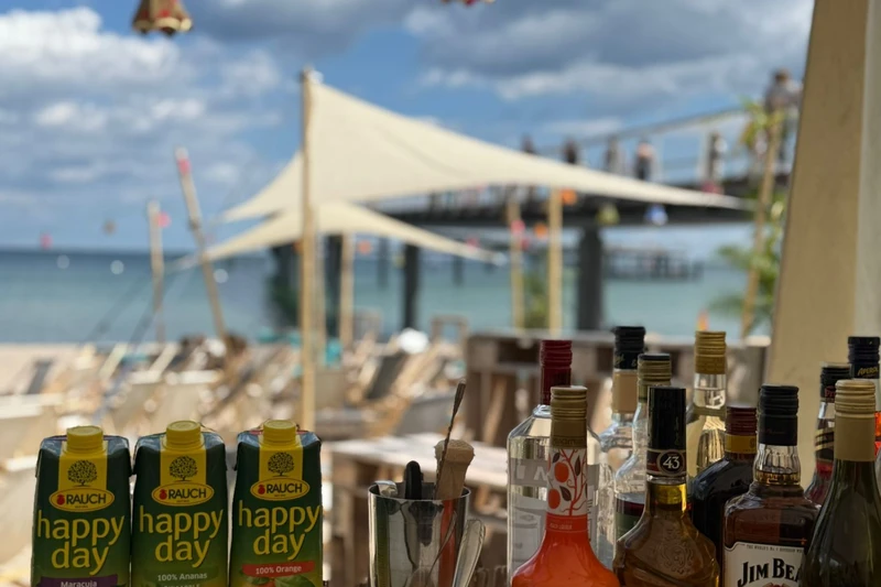 Getränke die auf einem Tisch stehen und im Hintergrund eine Lounge am Strand 