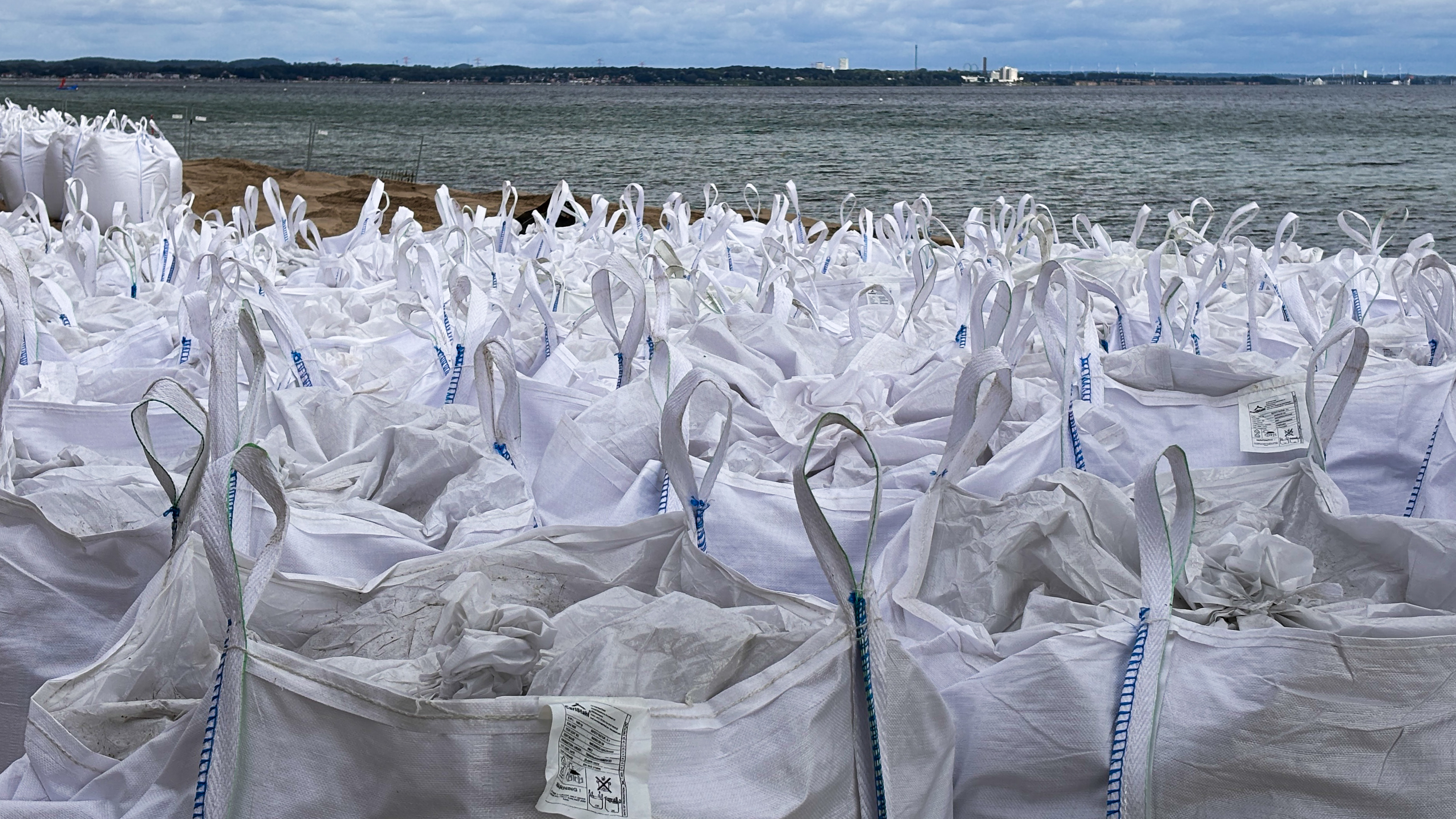 Viele weiße Big Bags aus weißem Polypropylengewebe mit Sand gefüllt am Strand