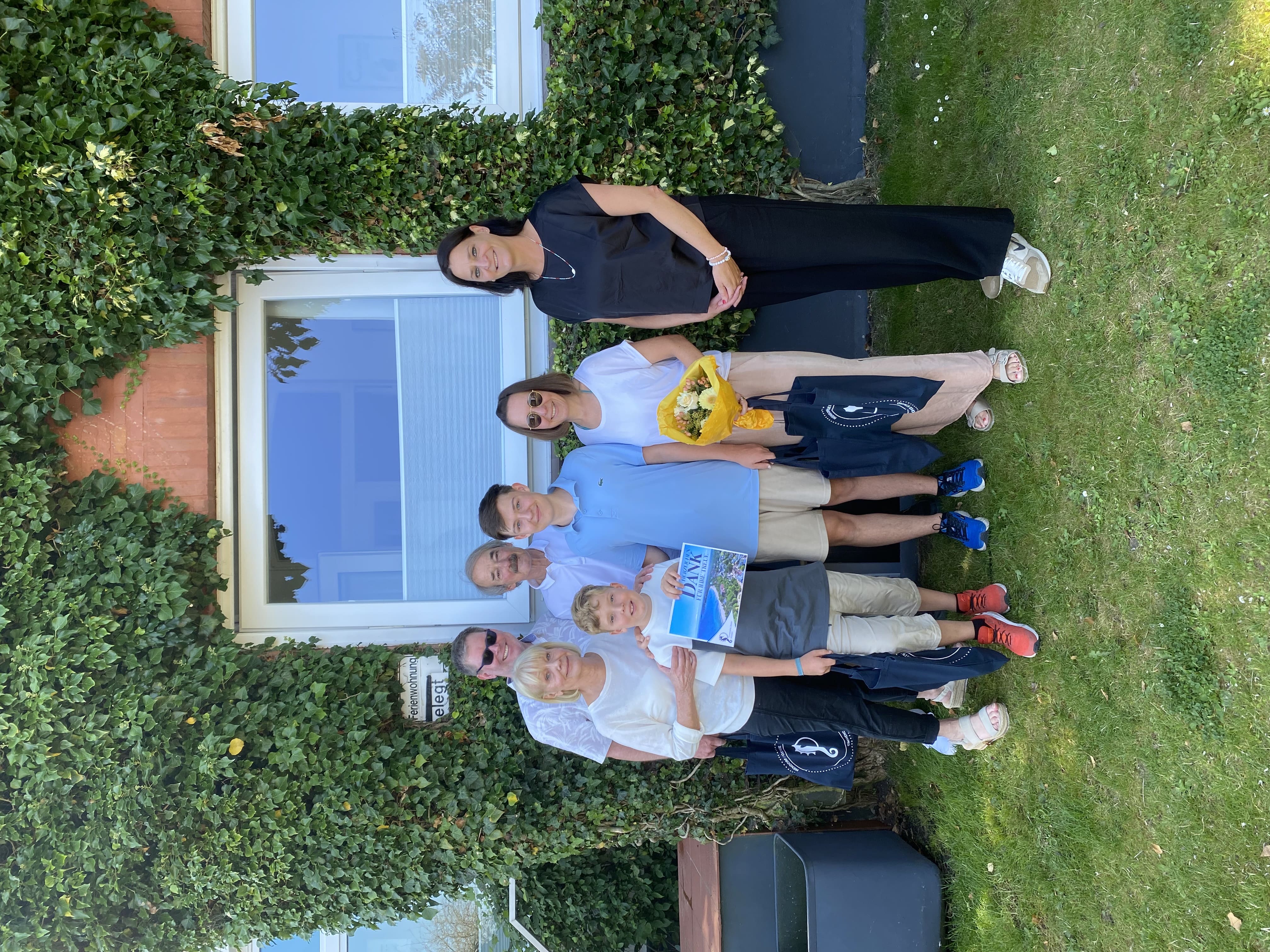 Foto einer Familie, die vor einer efeubewachsenen Wand steht