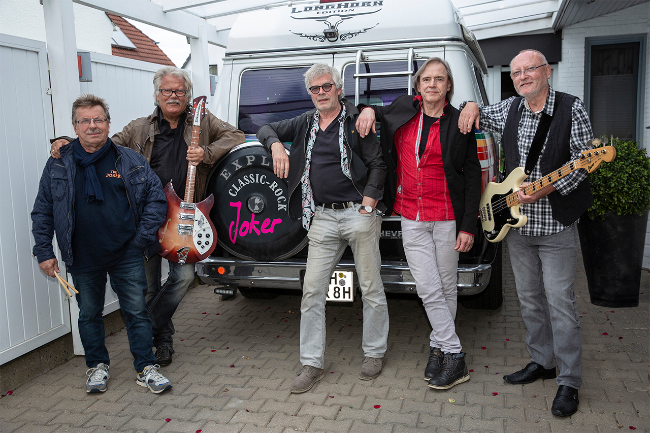Bandfoto der Band The Joker neben ihrem Tourbus
