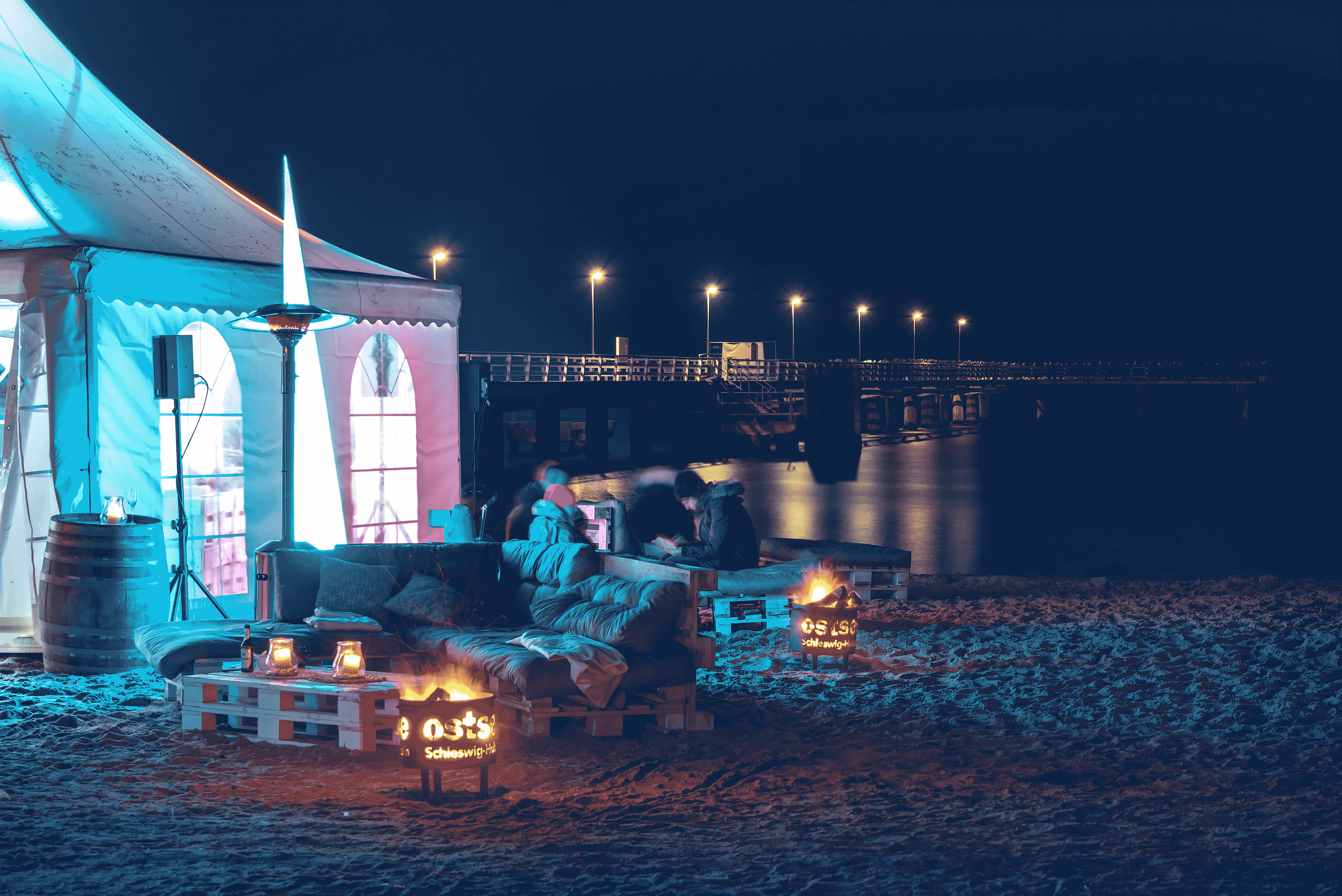 Festzelt und Sitzbänke am Strand bei Nacht