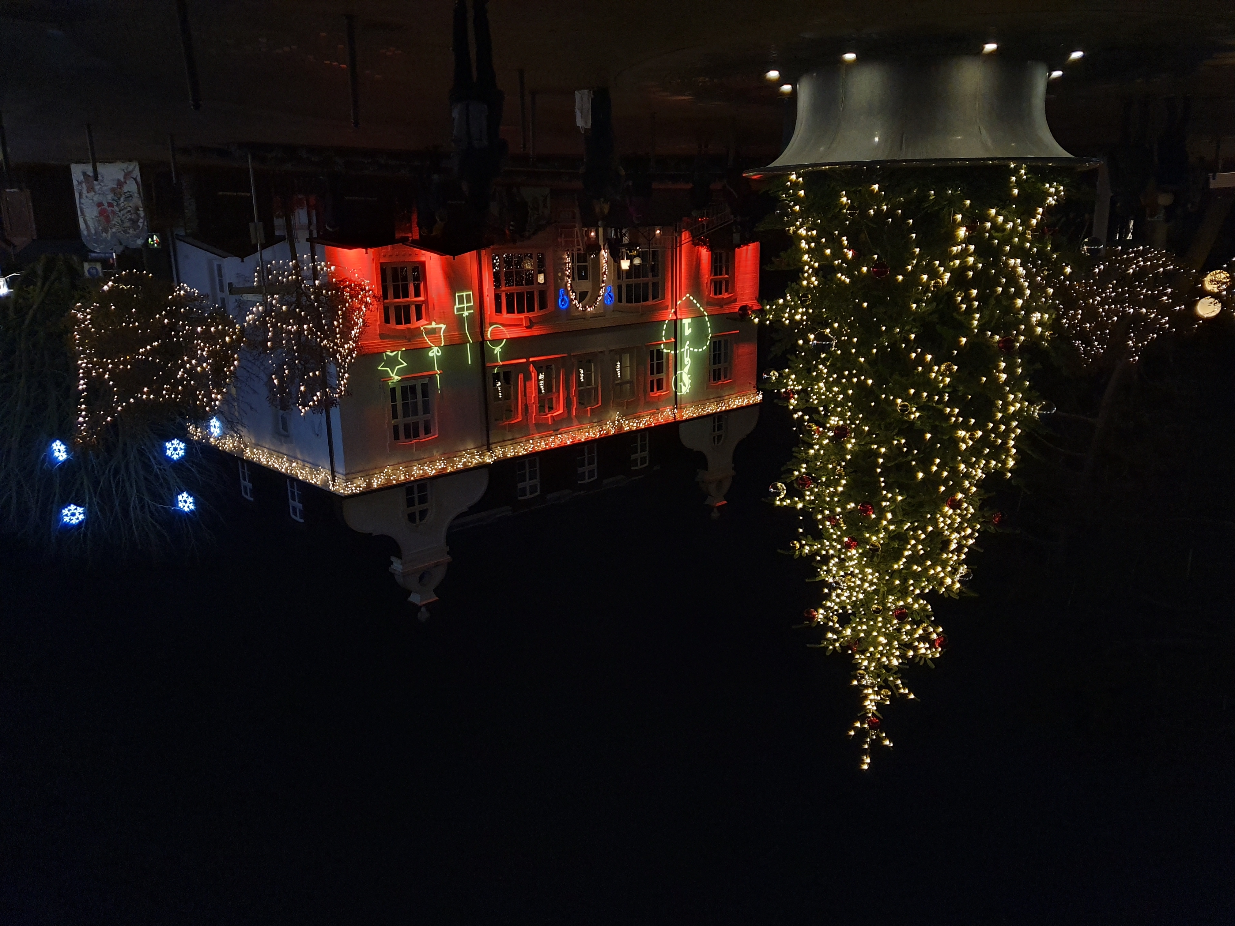 Weihnachtlich geschmücktes Gebäude mit geschmückter Tanne davor bei Nacht