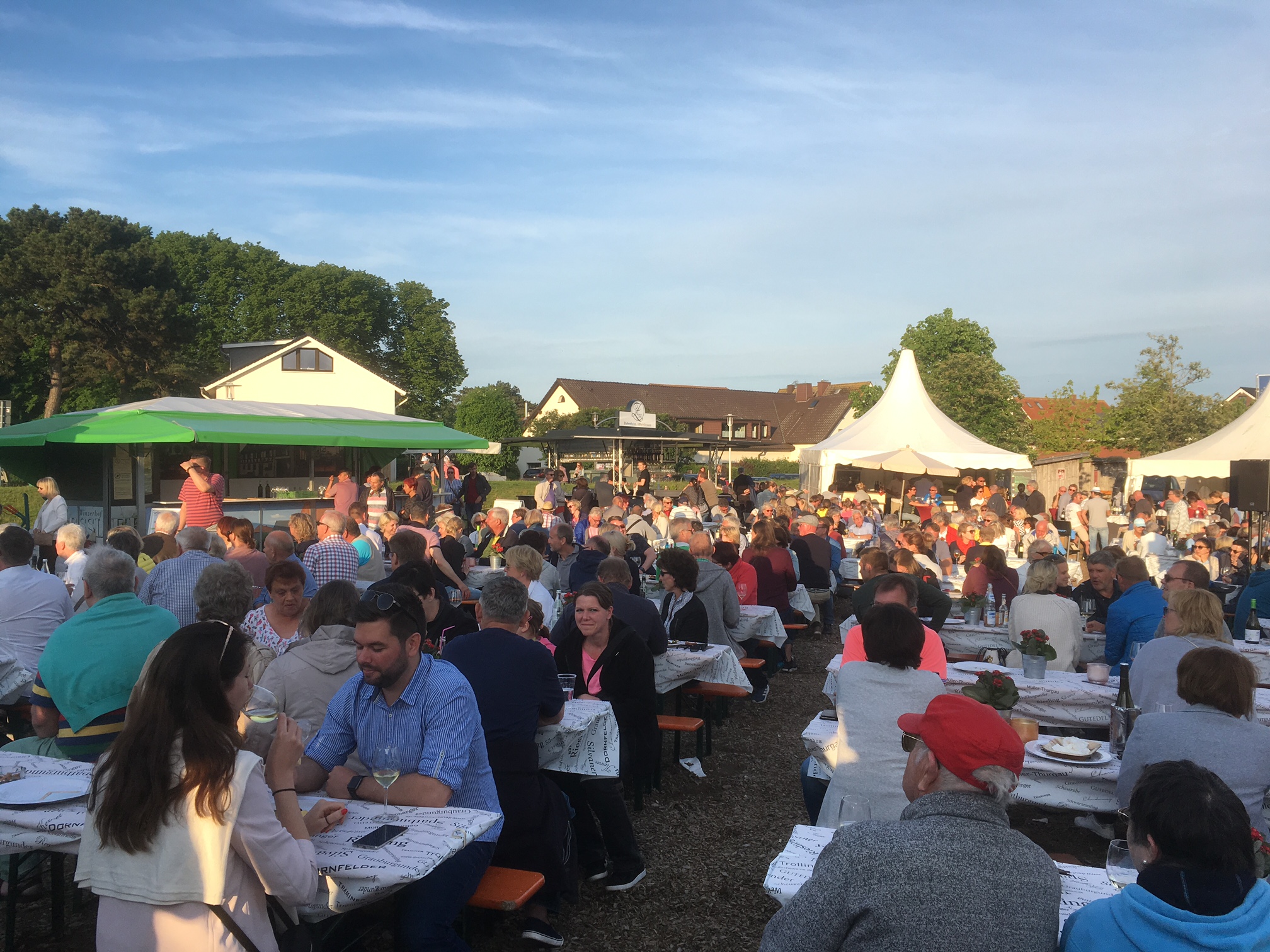 Viele Menschen sitzen draußen an Tischen