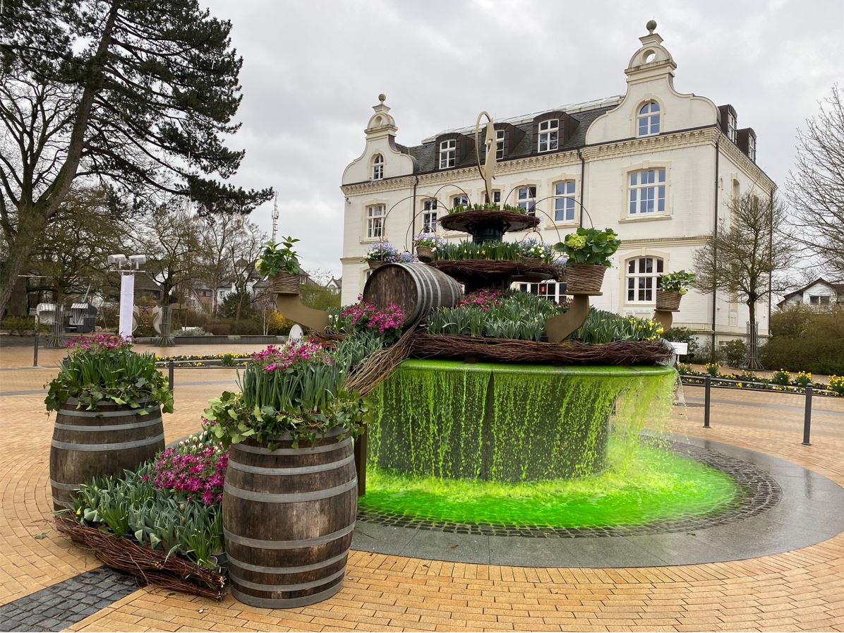 Grün leuchtender Osterbrunnen in voller Blütenpracht