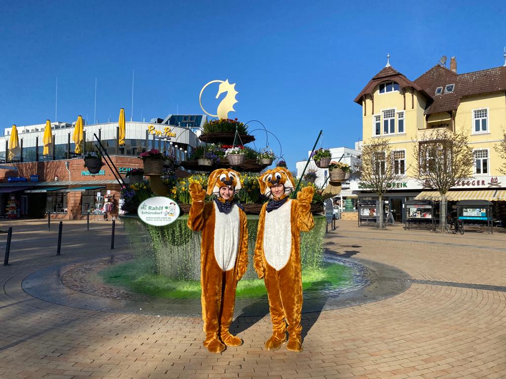 Zwei als Hasen verkleidete Personen stehen auf dem Timmendorfer Marktplatz vor dem Brunnen