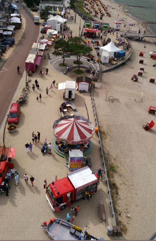 Festmeile aus der Luft fotografiert. Zu sehen ist ein Karussell, Feuerwehrautos und viele Menschen.