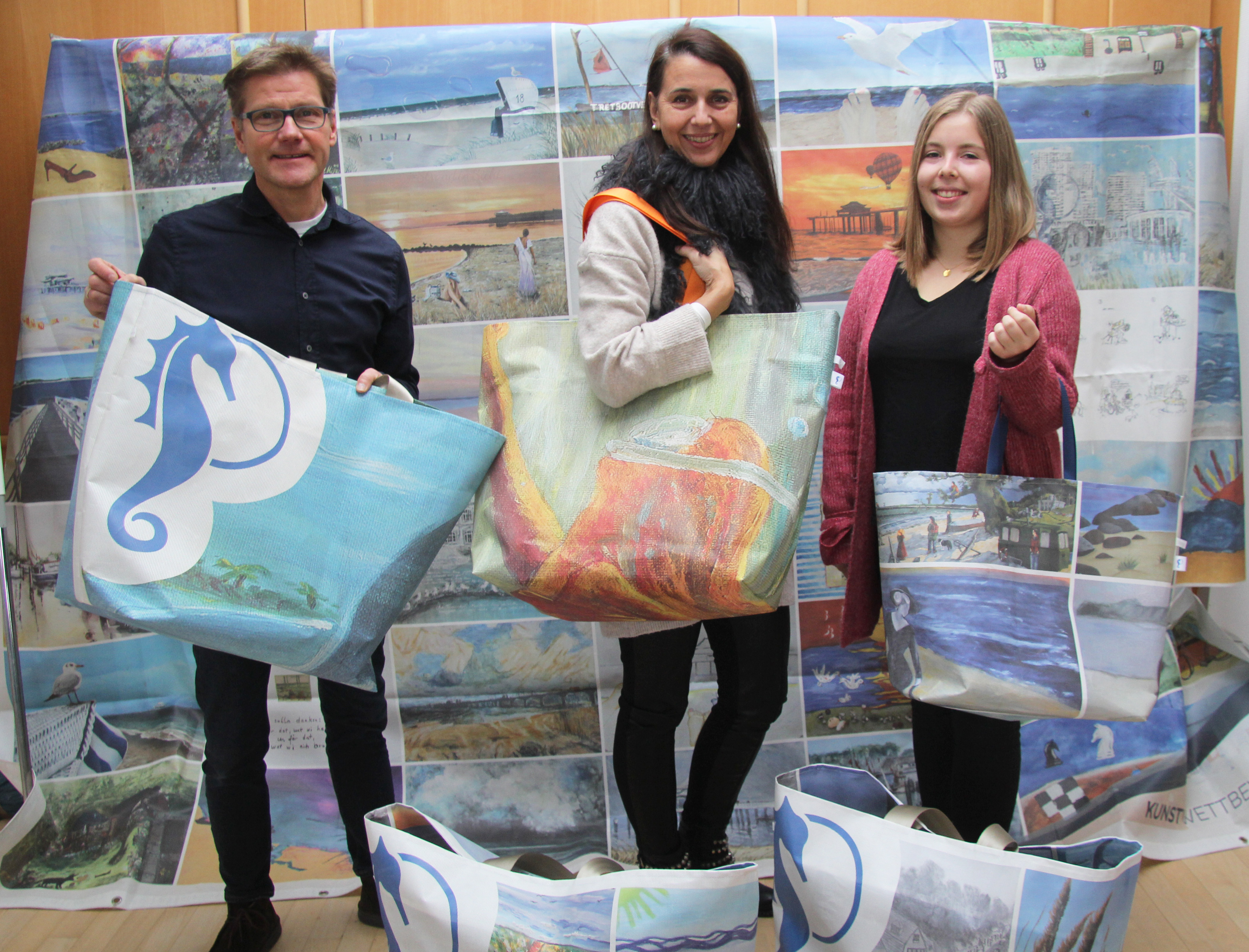Drei Personen präsentieren große bunte Taschen mit Motiven