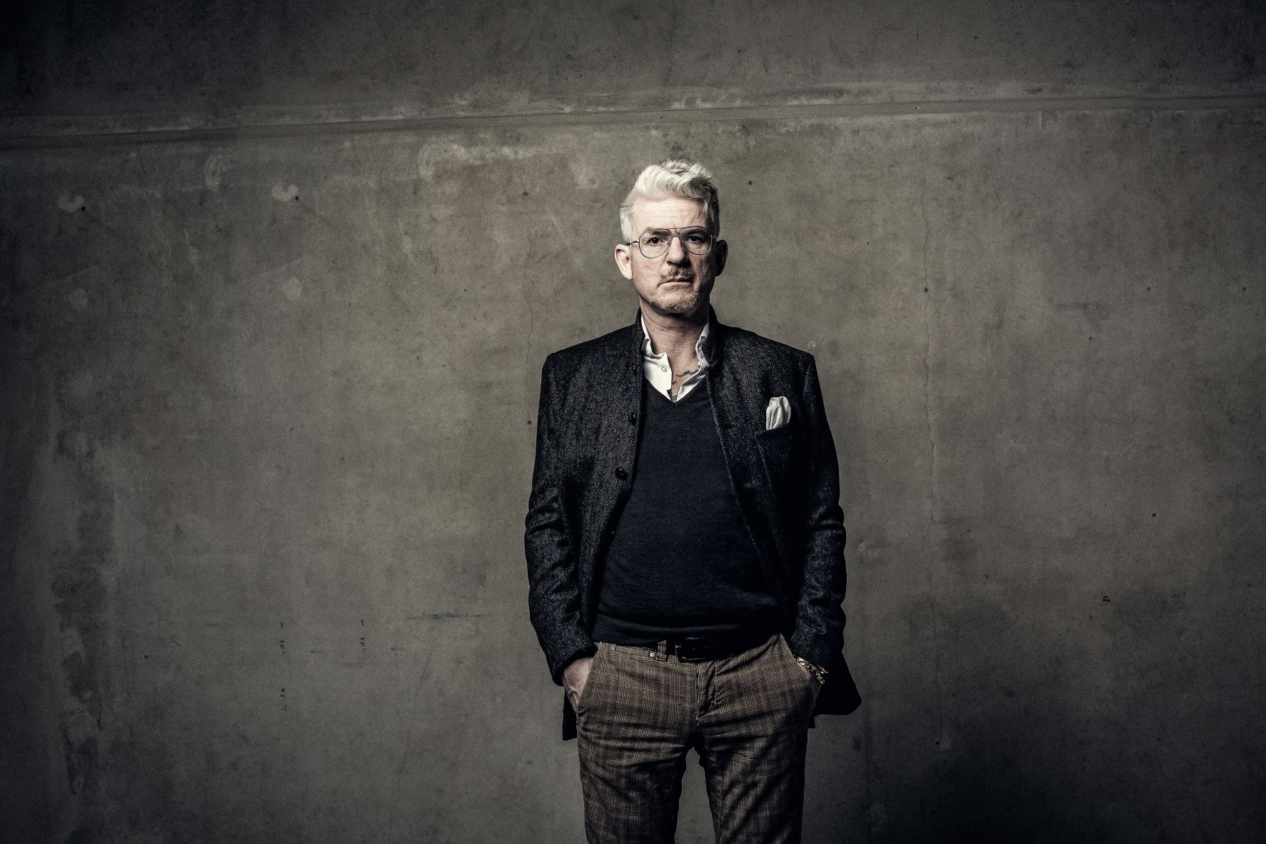 Porträtfoto von Heinz Strunk vor einer grauen Wand