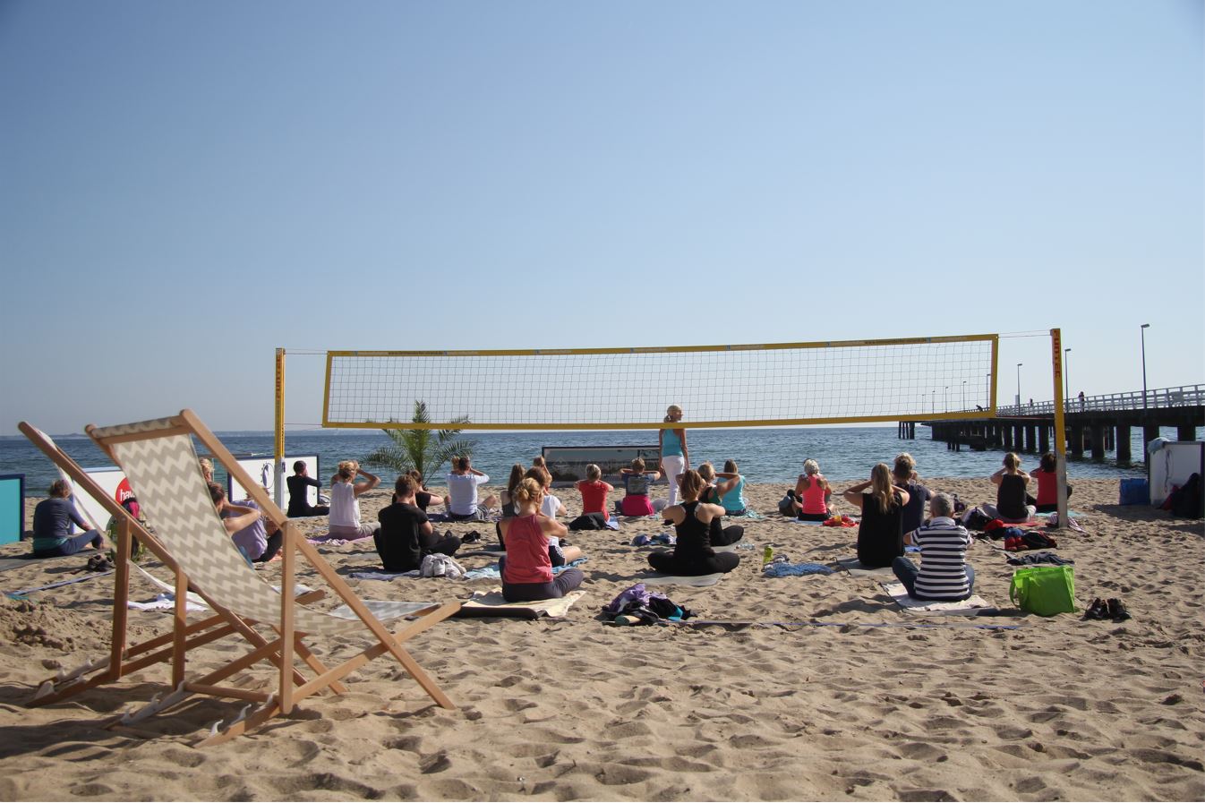 Eine Gruppe macht Yoga auf einem Beachvolleyballfeld