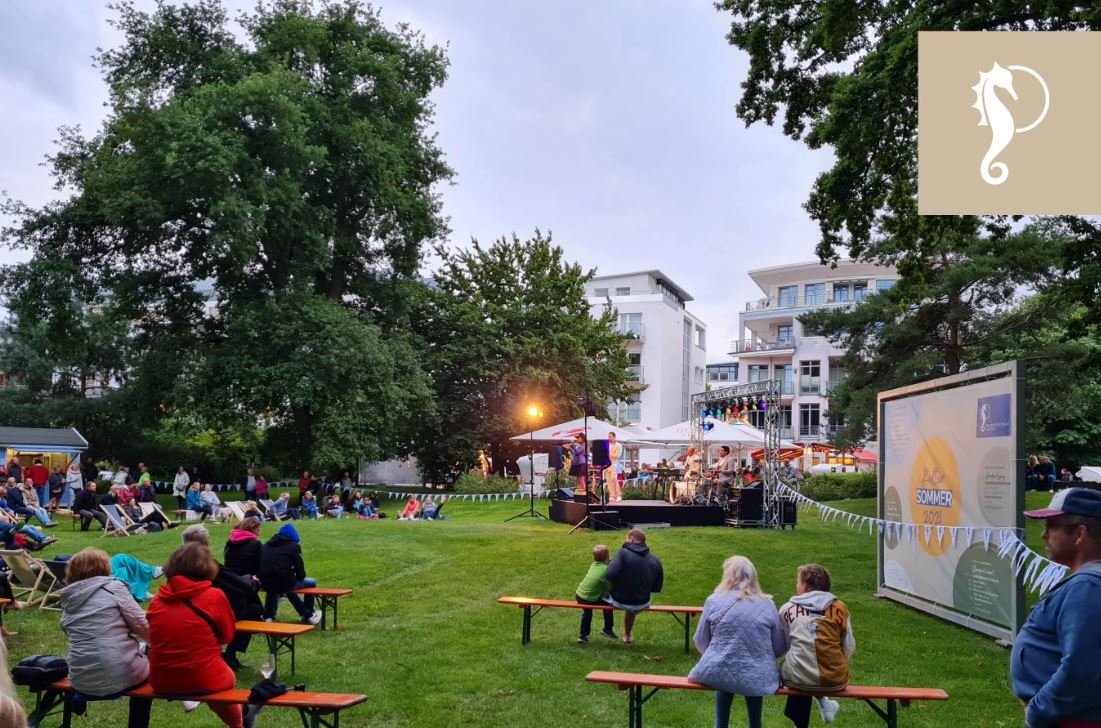 Konzert im Strandpark mit einer kleinen Bühne in der Mitte des Parks und Sitzgelegenheiten drum herum